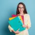 Young,Happy,Woman,Holding,Colorful,Binders,Isolated,On,The,Blue